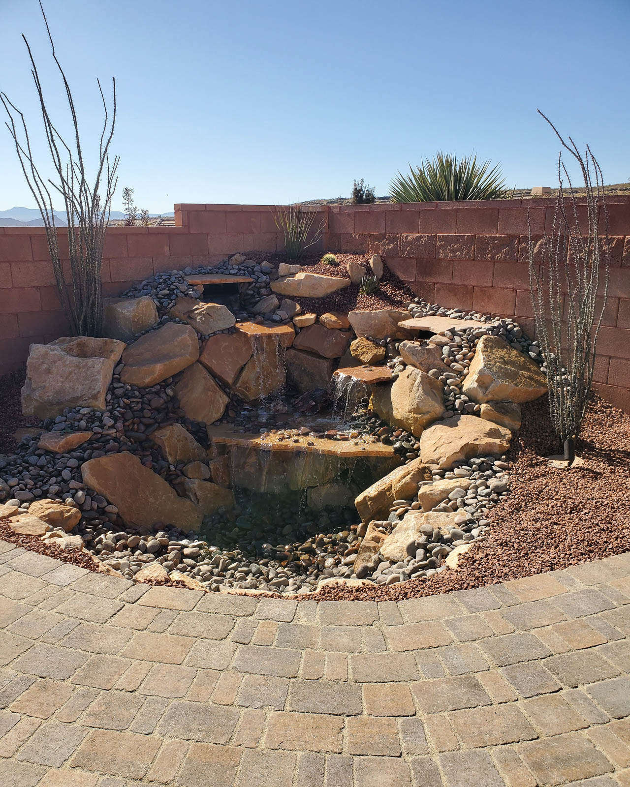 Backyard rock waterfall with paver walkway