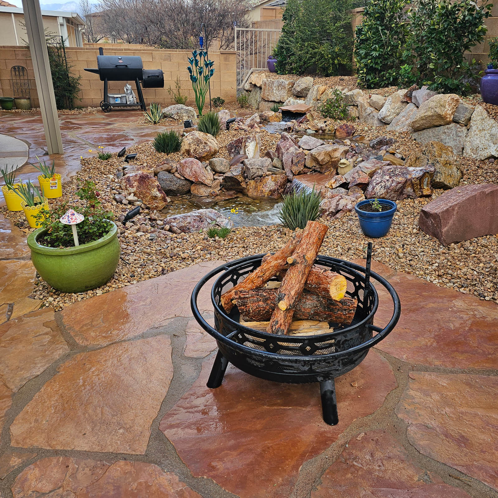 Flagstone patio with fire pit beside a rock garden and stream