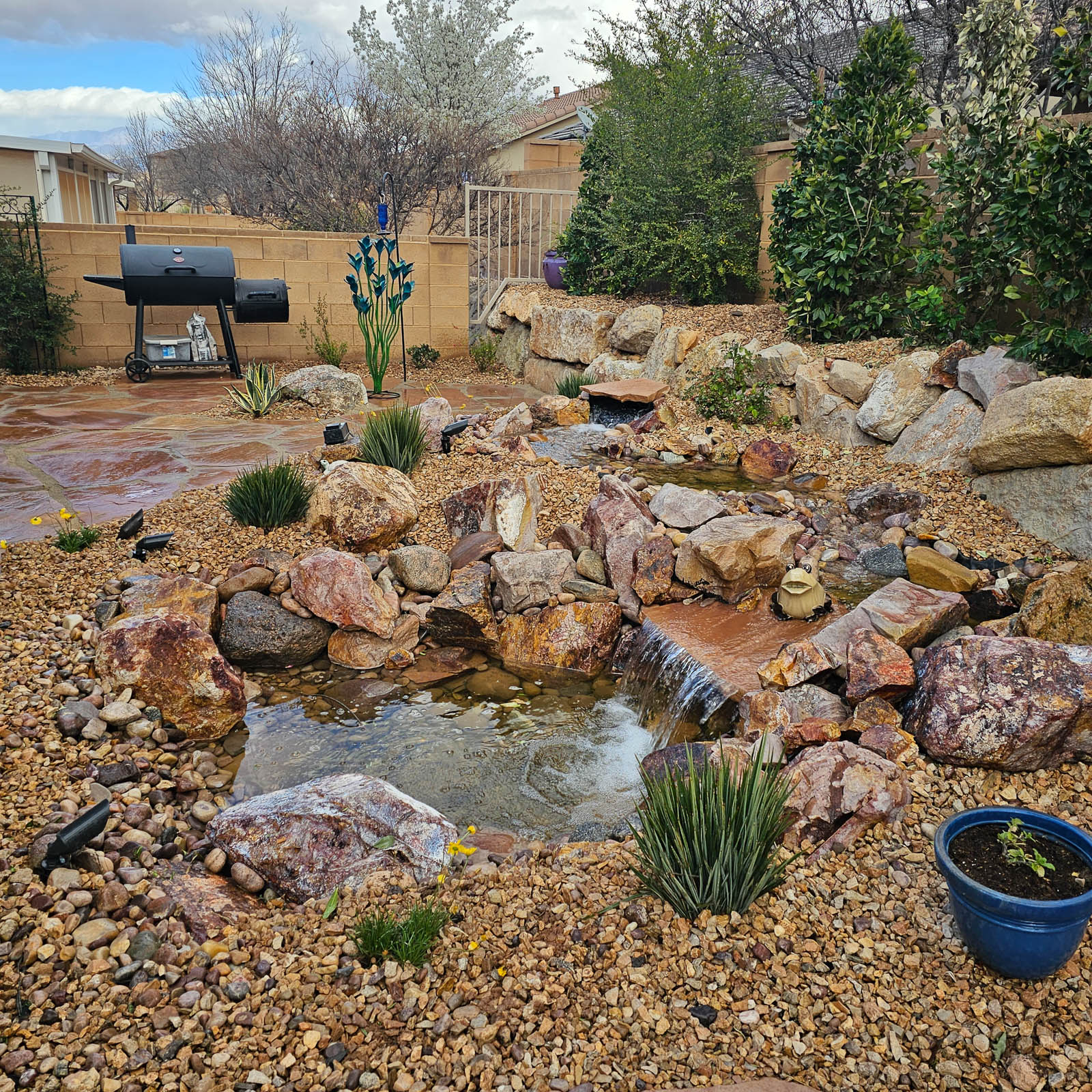 Backyard pond and rock stream surrounded by desert plants