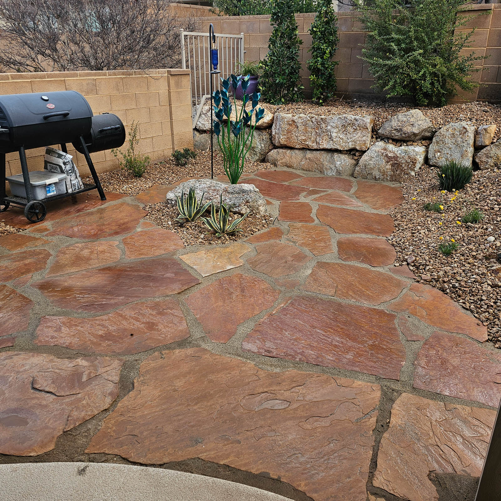 Red flagstone patio with boulder retaining wall