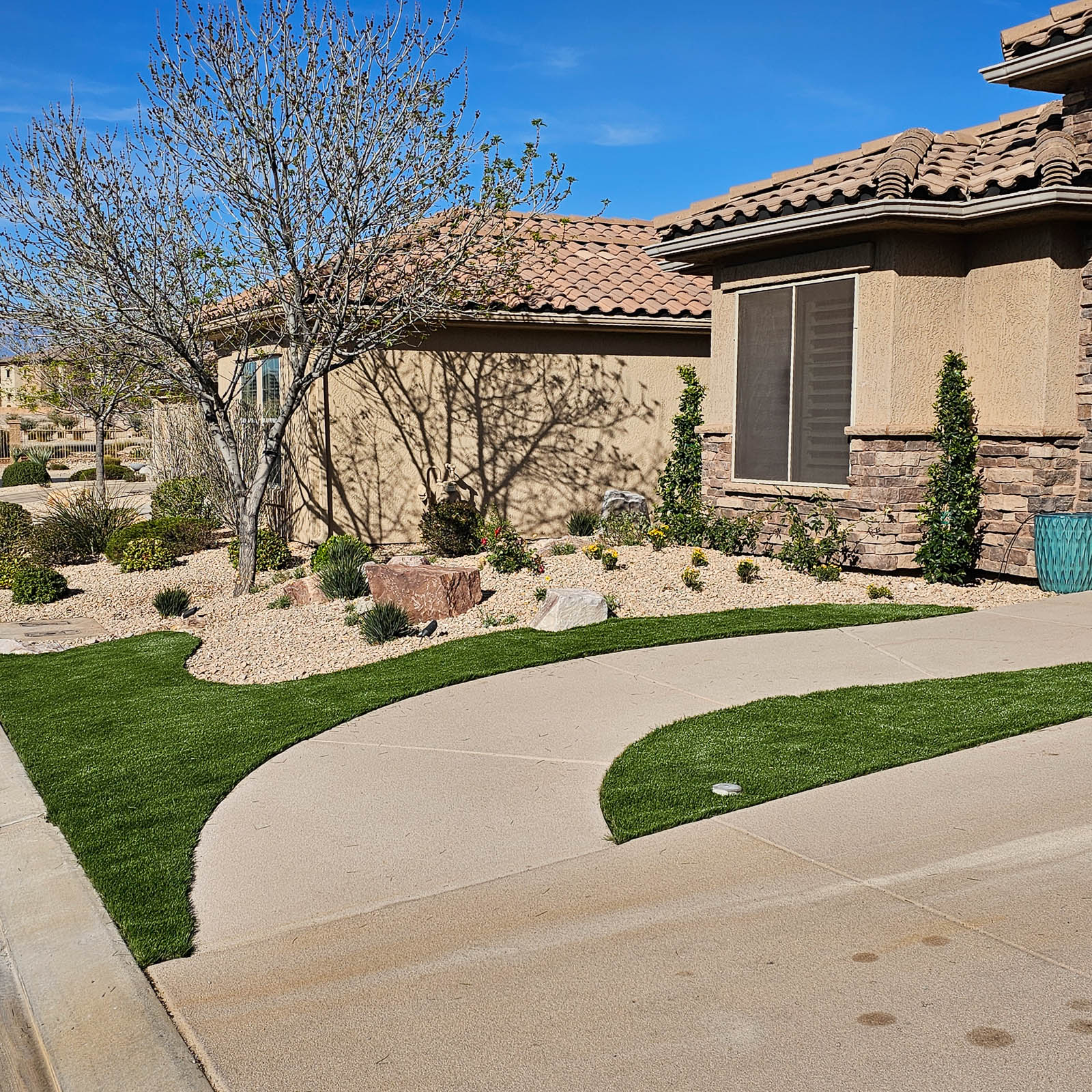 Front yard with curved concrete walkway, artificial turf and desert rock landscaping
