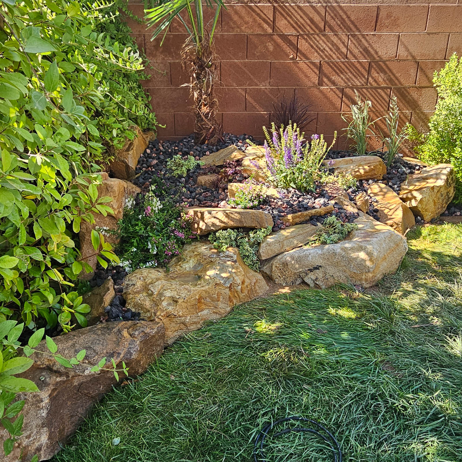 Lush planting bed with natural stone border and turf