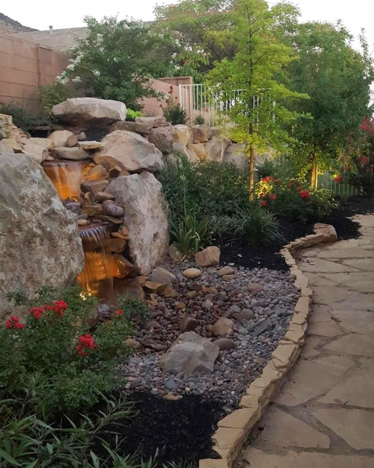 Lit waterfall beside a flagstone path