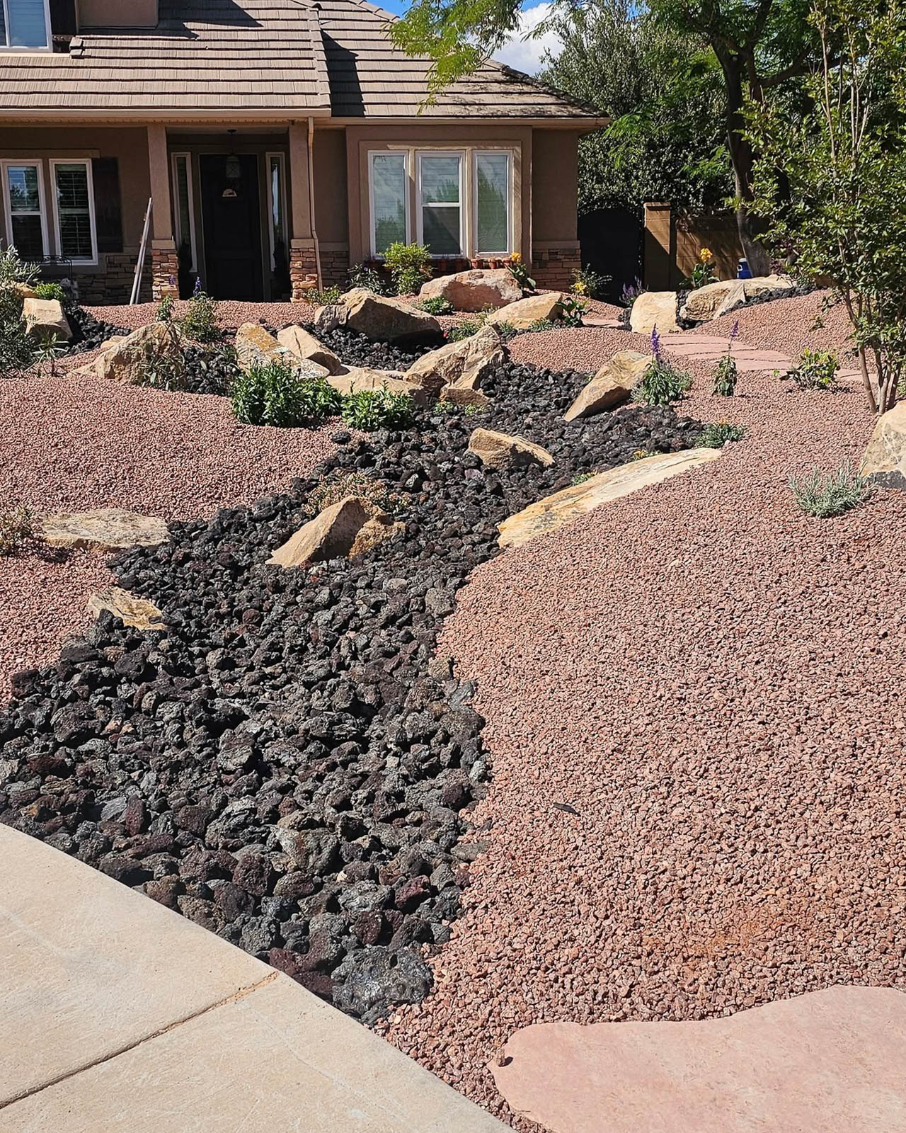 Front yard dry creek bed with lava rock and red gravel