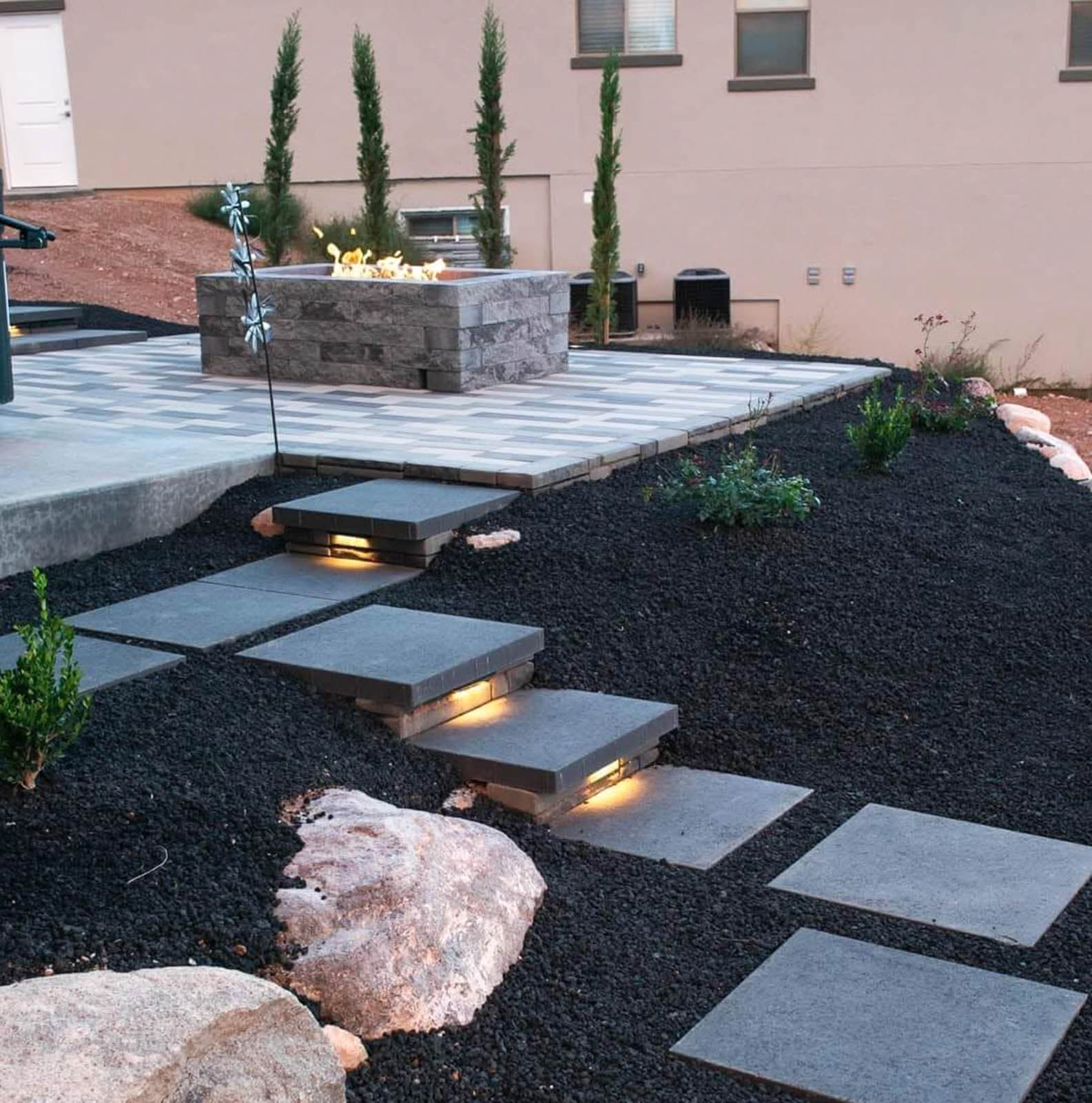 Lit floating steps leading to a stone fire pit