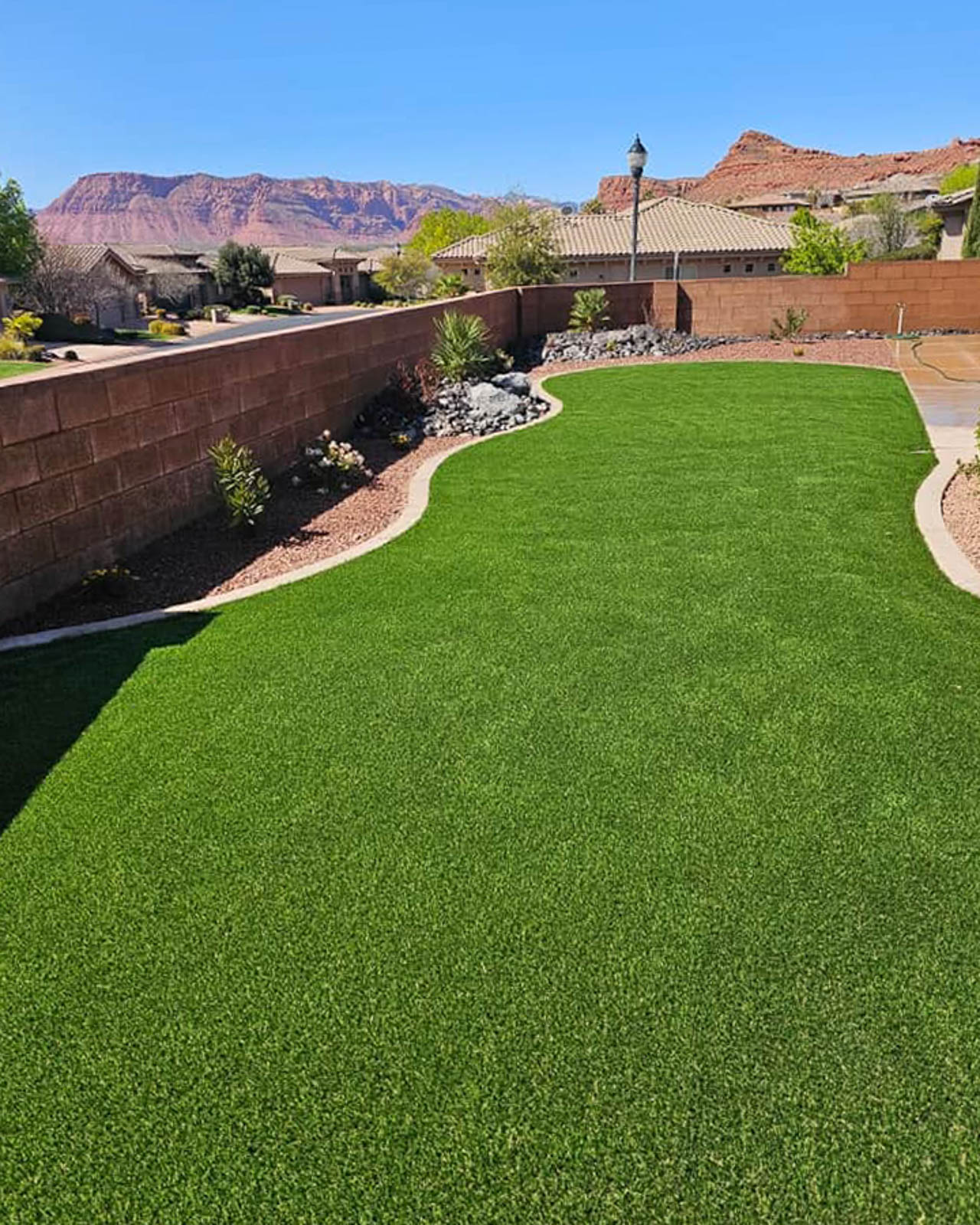 Curving artificial turf lawn with red rock cliffs in the background