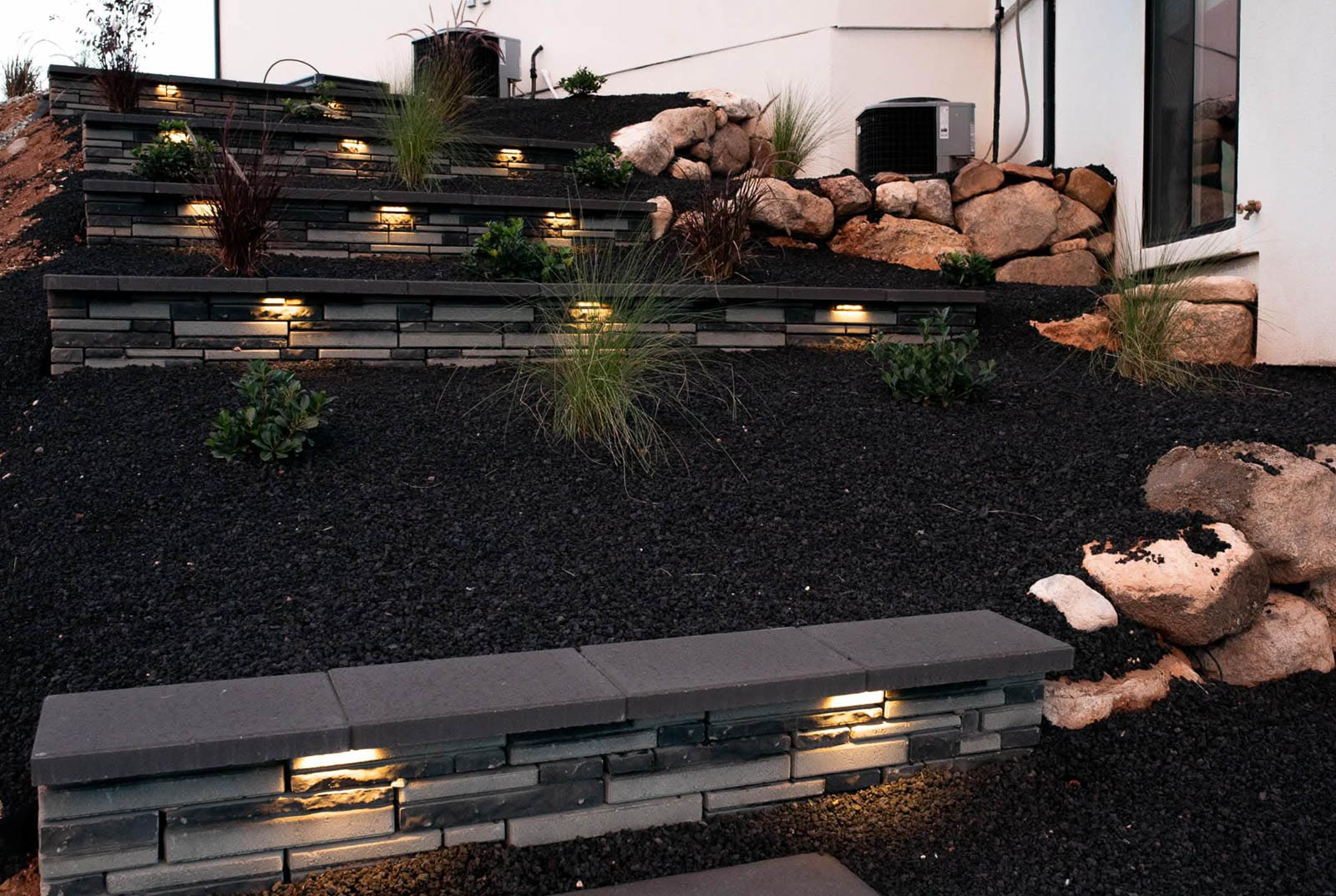Lit retaining walls with plantings and boulders